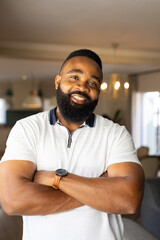 Smiling African American man with crossed arms standing confidently in modern home