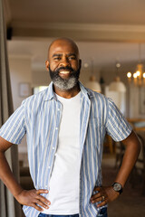 Smiling African American senior man standing confidently with hands on hips in modern home