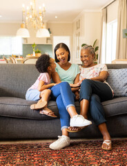 Sitting on couch, three generations of women laughing and bonding at home