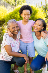 Smiling family outdoors, grandmother, mother, and daughter enjoying time together