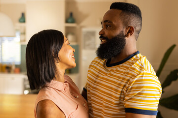 Smiling couple embracing and looking at each other in cozy home setting, in kitchen