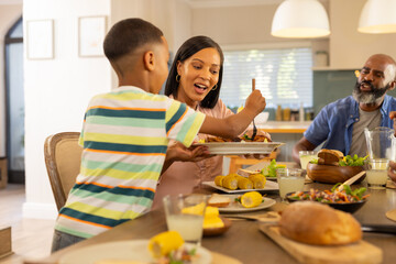 multigenerational family enjoying meal together at home, sharing food and smiling around table