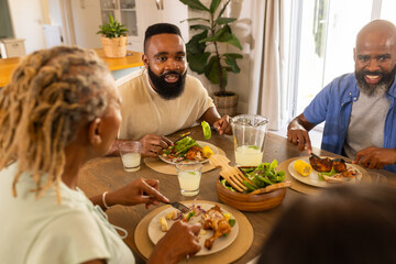 multigenerational family enjoying meal together, sharing food and conversation at dining table