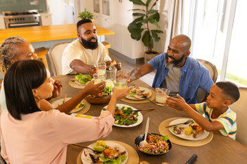 multigenerational family enjoying dinner together, raising glasses for toast at home