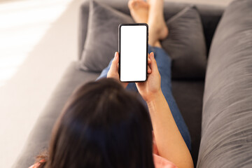 Holding smartphone, Asian woman relaxing on couch and browsing blank screen