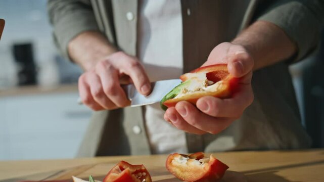 Man hands slicing pepper on kitchen closeup. Unknown guy preparing ingredients