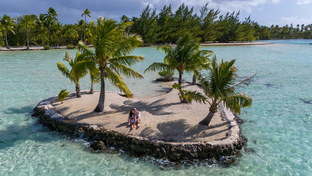A man and woman alone together on a tiny tropical island in the shape of a heart. The romantic getaway is a private vacation for the married couple in paradise. 