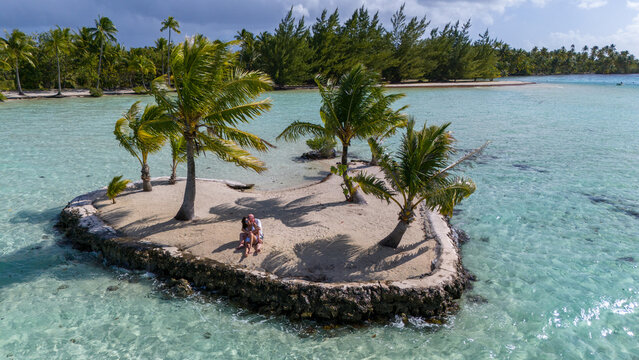 A man and woman alone together on a tiny tropical island in the shape of a heart. The romantic getaway is a private vacation for the married couple in paradise. 