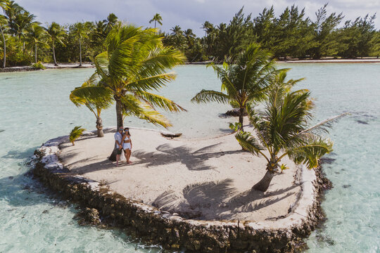 A man and woman alone together on a tiny tropical island in the shape of a heart. The romantic getaway is a private vacation for the married couple in paradise. 