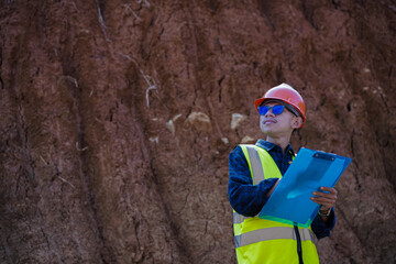 A male construction worker is inspecting and recording data in the field