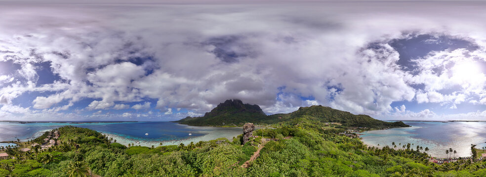 Panoramic view of the tropical island Bora Bora in French Polynesia. The popular tourist destination is paradise covered with palm trees and surrounded by beautiful blue and azure South Pacific ocean.
