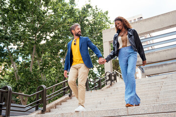 Joyful couple walking hand in hand down city stairs
