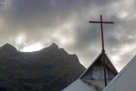 Christian cross seen on the church &Eacute;glise Saint-Pierre-C&eacute;lestin on tropical island Bora Bora under a dark cloudy sky. 