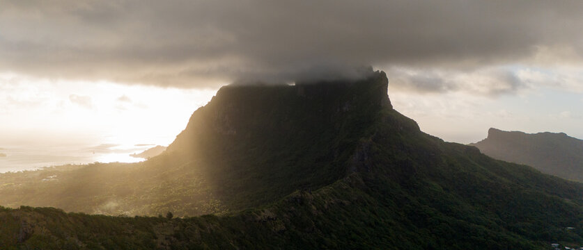 Sunset over Mount Otemanu on tropical island Bora Bora in French Polynesia. Low clouds float above the extinct volcano on the popular tourist destination in the south pacific sea. 