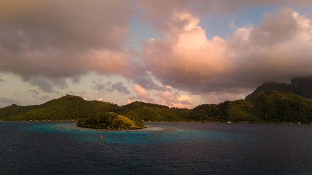 Early sunrise in the morning on tropical island Bora Bora in French Polynesia. Low clouds float above the popular tourist destination in the south pacific sea. 