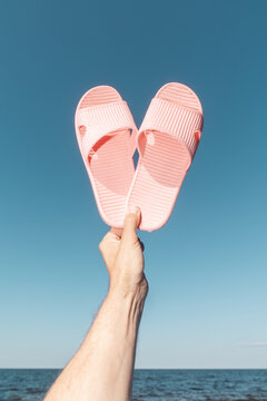 Hand Holding Pink Beach Sleepers Against Blue Sky