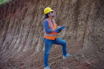 A male construction worker is inspecting and recording data in the field