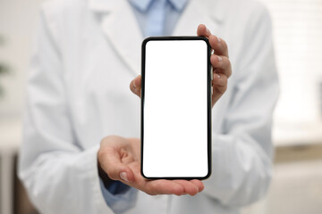 Doctor showing smartphone with blank screen in hospital, selective focus