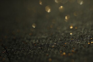 Beautiful shiny golden glitter on black background, closeup