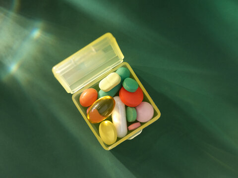 Set of many color pills in a yellow plastic pillbox