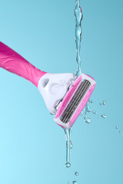 Pink Razor Under Running Water Against Blue Background