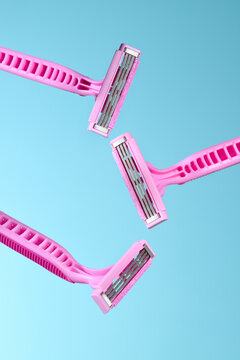Three Pink Razors Floating Against Blue Background
