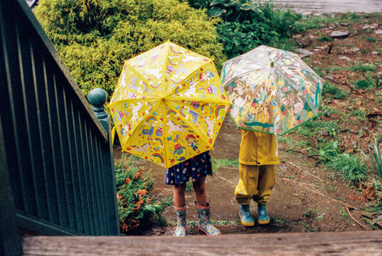Two Kids with Umbrellas Standing in the Rain
