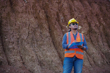 A male construction worker is inspecting and recording data in the field