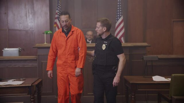 Police escorting inmate out from court room hearing