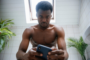 A man uses a mobile phone in the bathroom