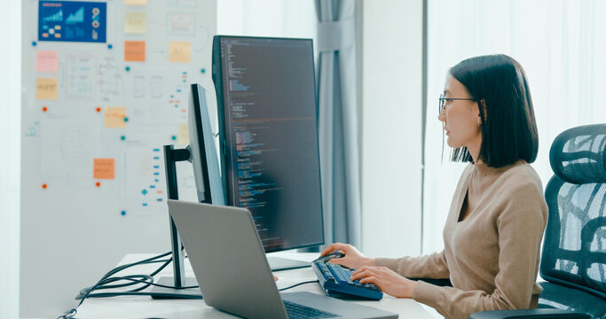 Young adult Asia female freelance eyeglasses typing write prompt AI bot IT app smart program nomad, video game, terminal with coding, user interface, designer, big data center on desktop computer.