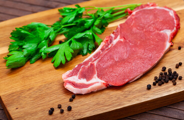 Ingredients for cooking. Raw beef entrecote with fresh parsley and spices on wooden surface