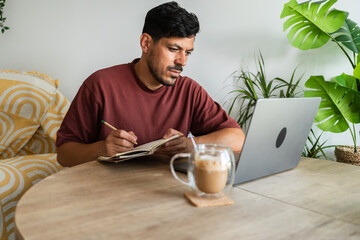 Focused freelancer working from home taking notes on notebook