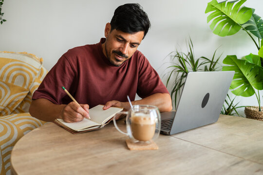 Focused man taking notes while working from home office