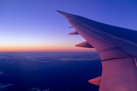 Airplane Wing Over Sunset-Hued Clouds at High Altitude