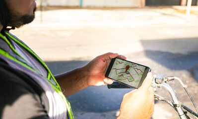 Latino worker in a shipping company checking the GPS to locate the next delivery