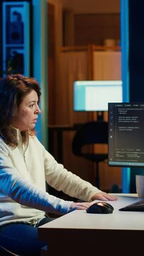 Vertical video Programmer stretches body limbs after securing company servers from virus attacks all day. Fatigued IT remote employee relaxing tense muscles at desk after building firewalls protecting