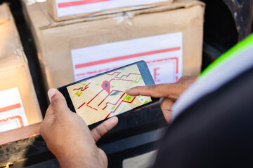 Horizontal photo of a Latino worker in a shipping company pointing to the GPS location on his phone...