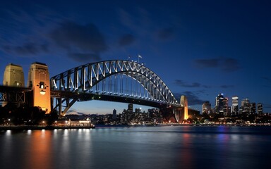 Fototapeta premium Harbour Bridge at Night: Illuminated Sydney Skyline with Reflections Background