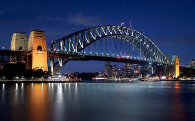Naklejka premium Harbour Bridge at Night: Illuminated Sydney Skyline with Reflections Background
