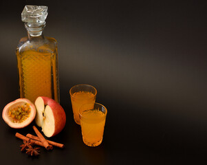 Passion fruit and apple liqueur with cinnamon and anise in a crystal decanter and two shot glasses...