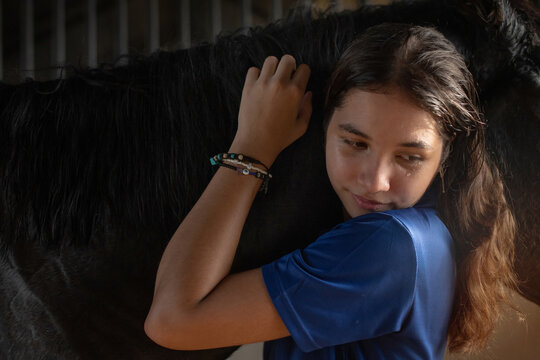Close up, teenage equestrian girl spends her time after training taking care of the horse she rides, embrace with love and affection equestrian sports, horse riding