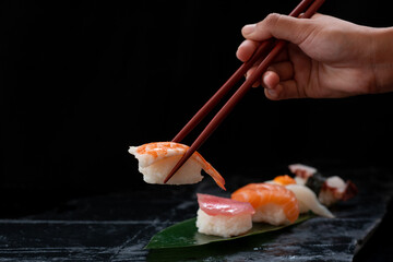 Close up, Japanese chef uses chopsticks to pick up shrimp sushi. traditional Japanese style food