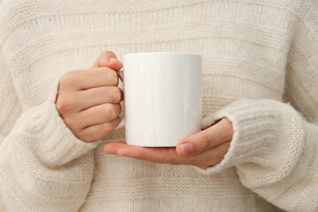 A woman holds a white cup in her hands