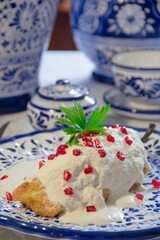 Chile en Nogada with walnut sauce served over talavera plate, vertical close-up.