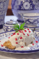 Chile en Nogada, roasted and stuffed poblano pepper with walnut white sauce and fresh pomegranate, served over talavera plate, vertical close-up.