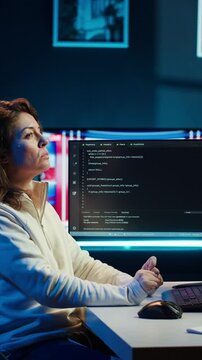 Vertical video IT specialist working from home, testing and deploying programs using augmented reality. Programmer checking code on computer monitor and AR visualization, sitting at desk chair in