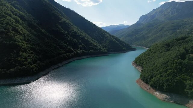 Flying over the turquiose lake Pivsko near Pluzine surrounded by green forrests and mountains in Montenegro druing august summertime