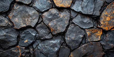 Fototapeta premium A close-up of a rough stone wall with a mix of dark and light grey stones.