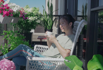 A woman has a cup of coffee/tea on the balcony